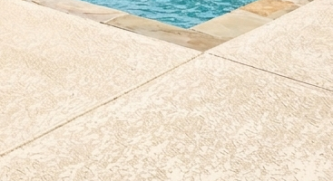 Close-up detail of a Noble Elegance textured pool deck overlay, showing the slip-resistant hand-troweled finish and durable light-tan protective coating.